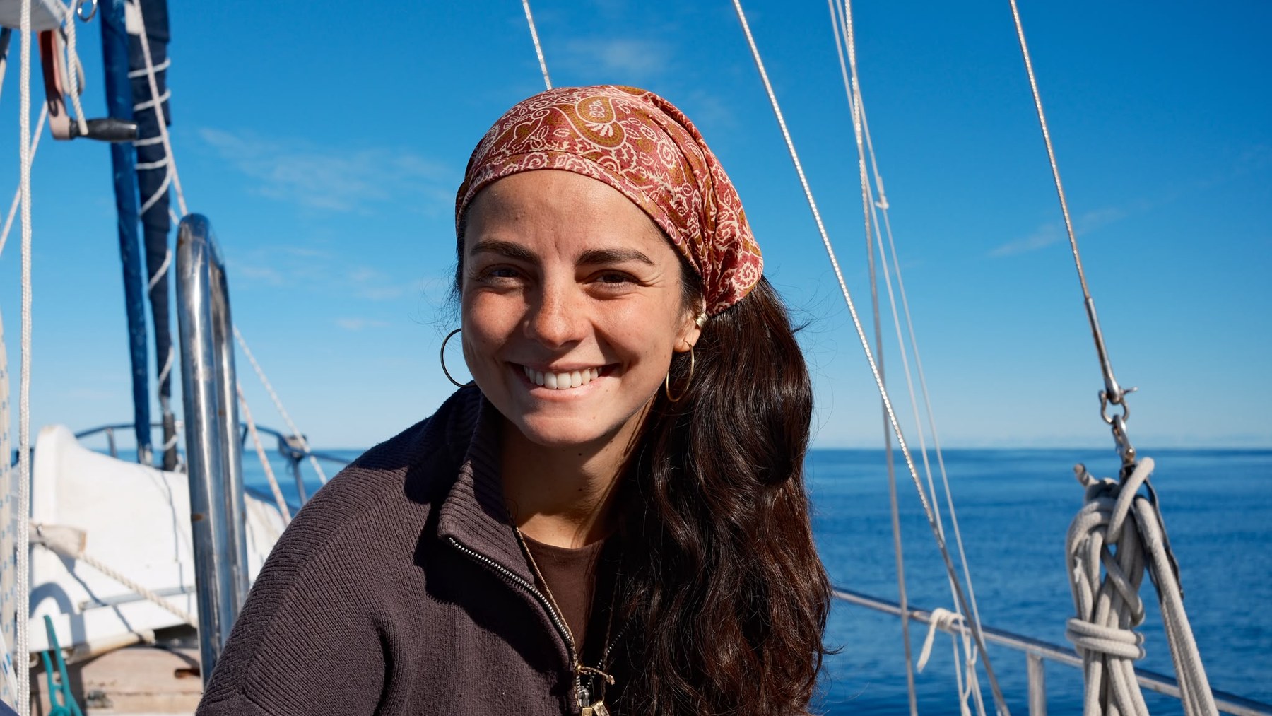 A Dog Star student on deck, mid-ocean, sailing rigging framing an open horizon