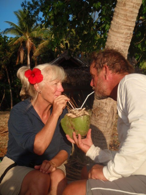 Diana and Alvah Simon sharing a green coconut on a tropical beach